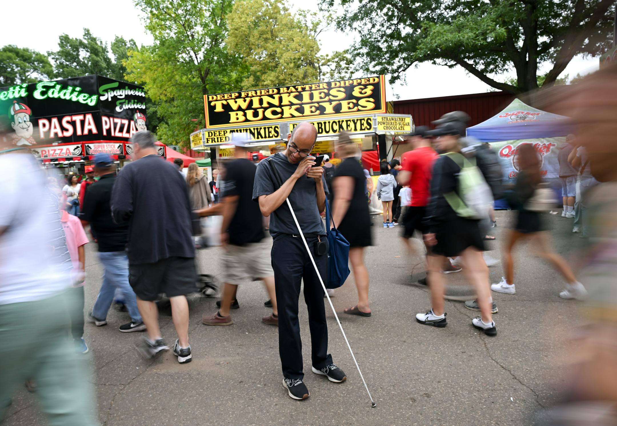 Paivy Ballayan, of Roseville, who was born blind, uses a combination of apps, including Google Maps and Lazarillo, to navigate the fair Saturday, Aug. 26, 2023 at the Minnesota State Fairgrounds in Falcon Heights, Minn. Phones frequently have bad or no service at the fair, and that complicates navigation efforts for visually impaired people.