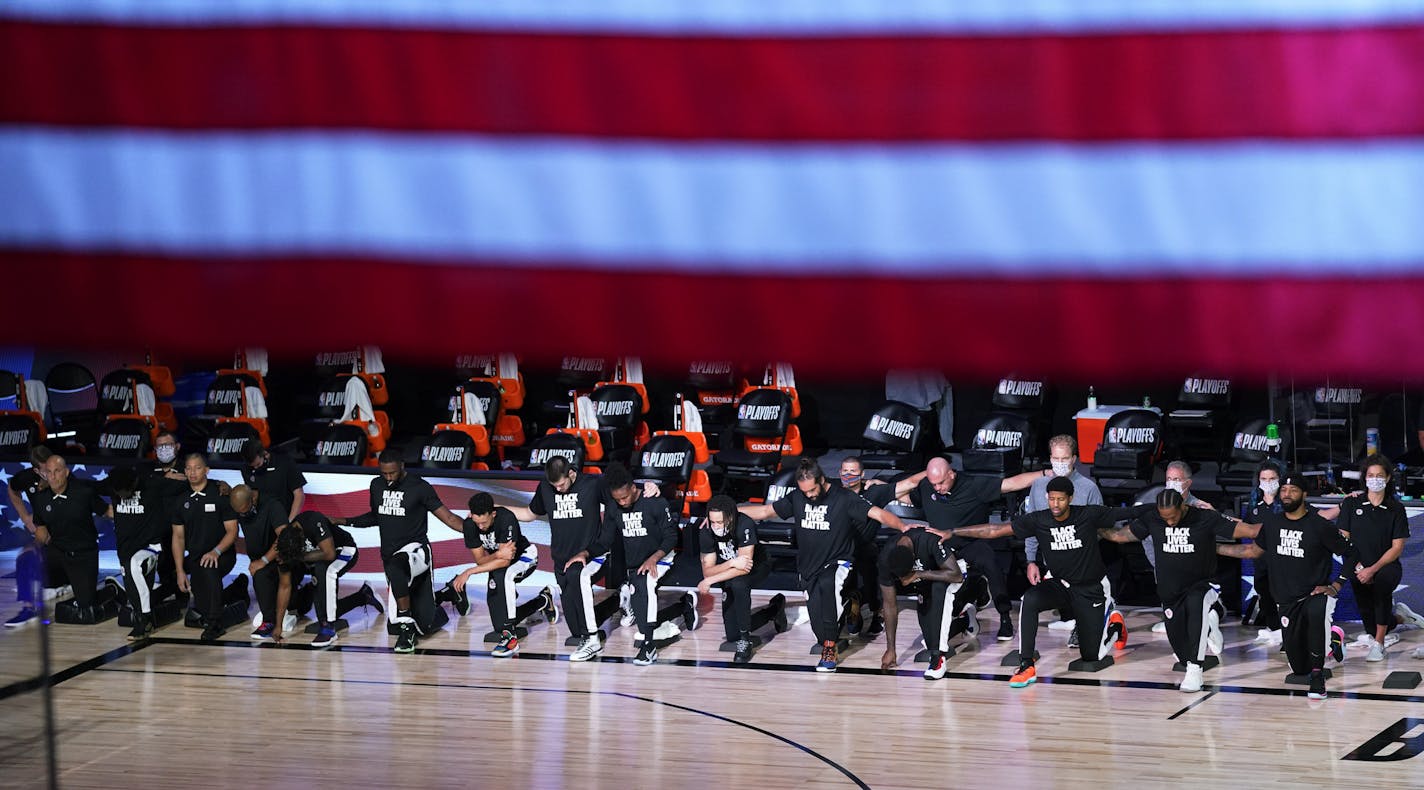 Los Angeles Clippers players and personnel keel during the national anthem before an NBA conference semifinal playoff basketball game against the Denver Nuggets, Friday, Sept. 11, 2020, in Lake Buena Vista, Fla. (AP Photo/Mark J. Terrill)