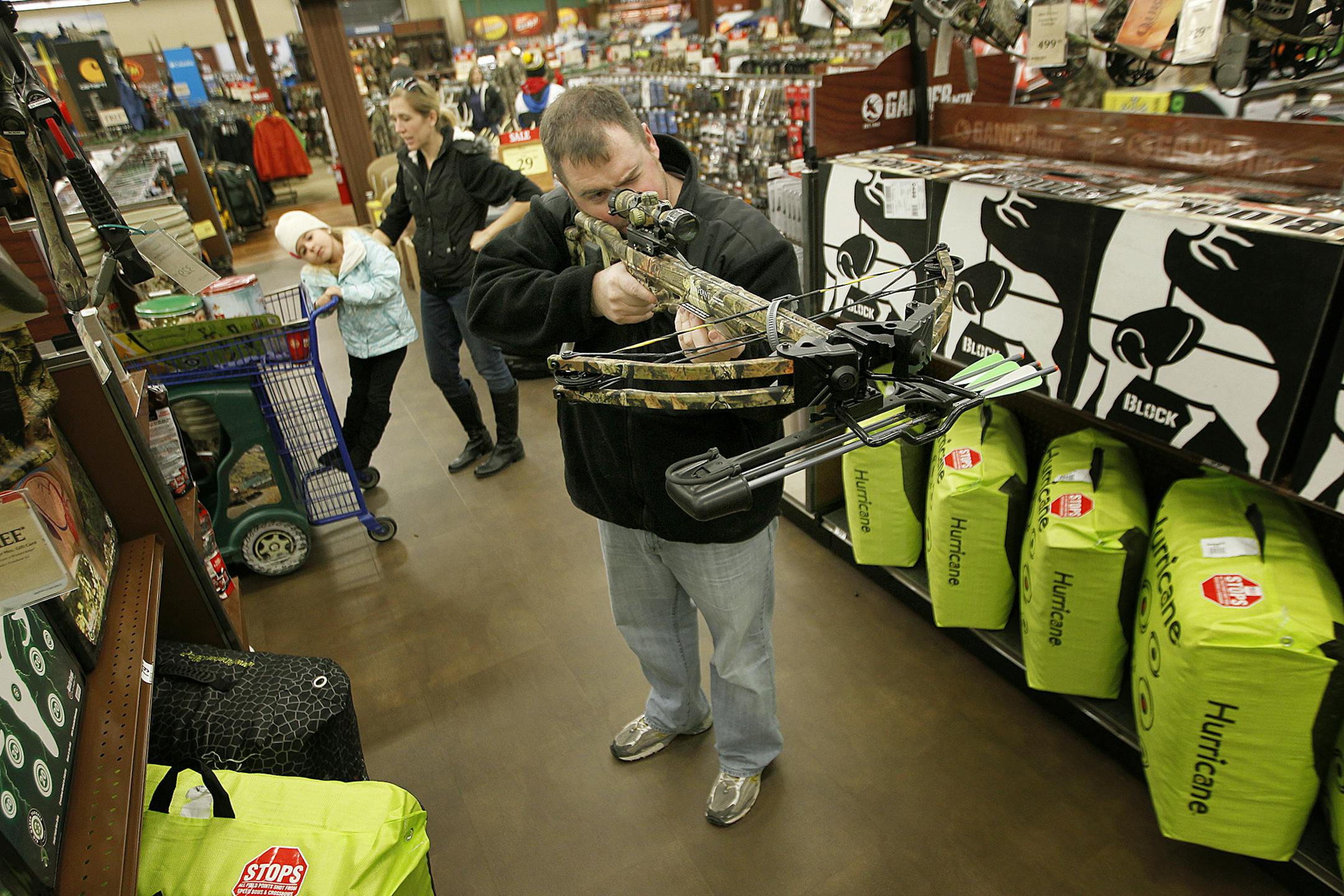 T.J. Kvilhaug, checked out a bow, along with his wife Bria, center, and two daughters Madison, 5, left, and Avery, 3, during "Black Friday" shopping at Gander Mountain, in Woodbury, MN. (ELIZABETH FLORES/STAR TRIBUNE) ELIZABETH FLORES • eflores@startribune.com