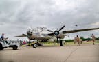 After hitting the skies, "Miss Mitchell," a B-25, is pushed into a parking spot as a helicopter goes by during Aviation Days at the Anoka County Airpo
