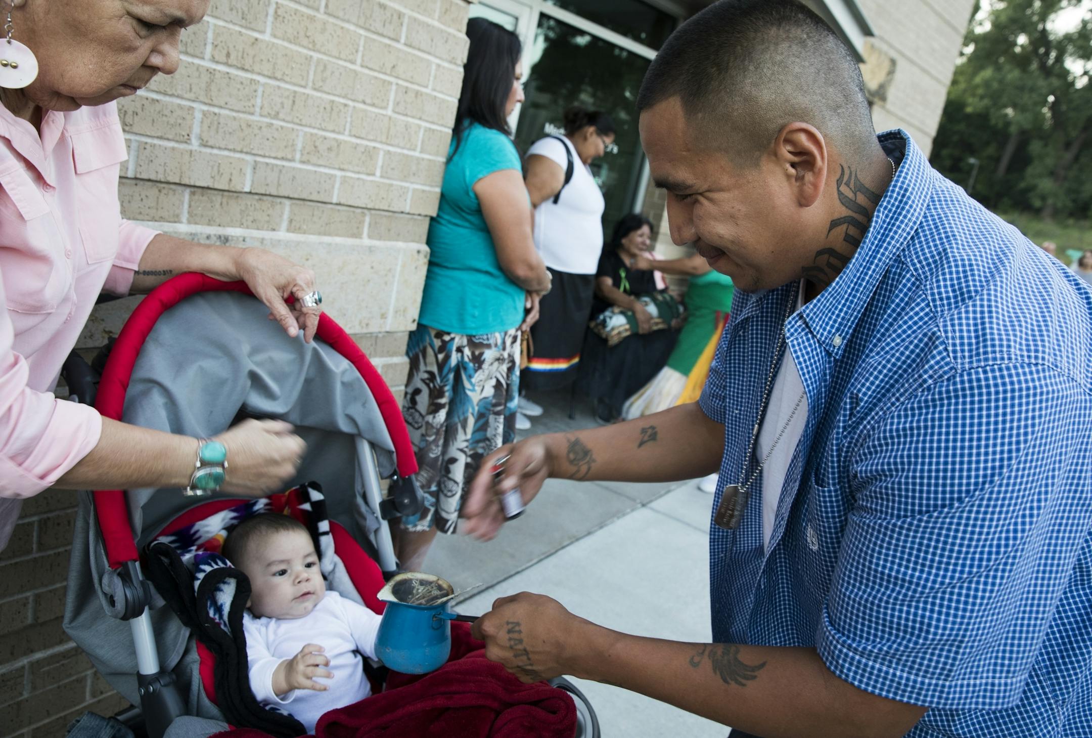 Three-month-old Mukwayun Lodge receives cleansing smoke during a prayer circle for Savanna LaFontaine-Greywind.
