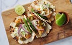 Three Pan-Fried Crispy Fish Tacos with Creamy Cilantro Slaw on a wooden cutting board.