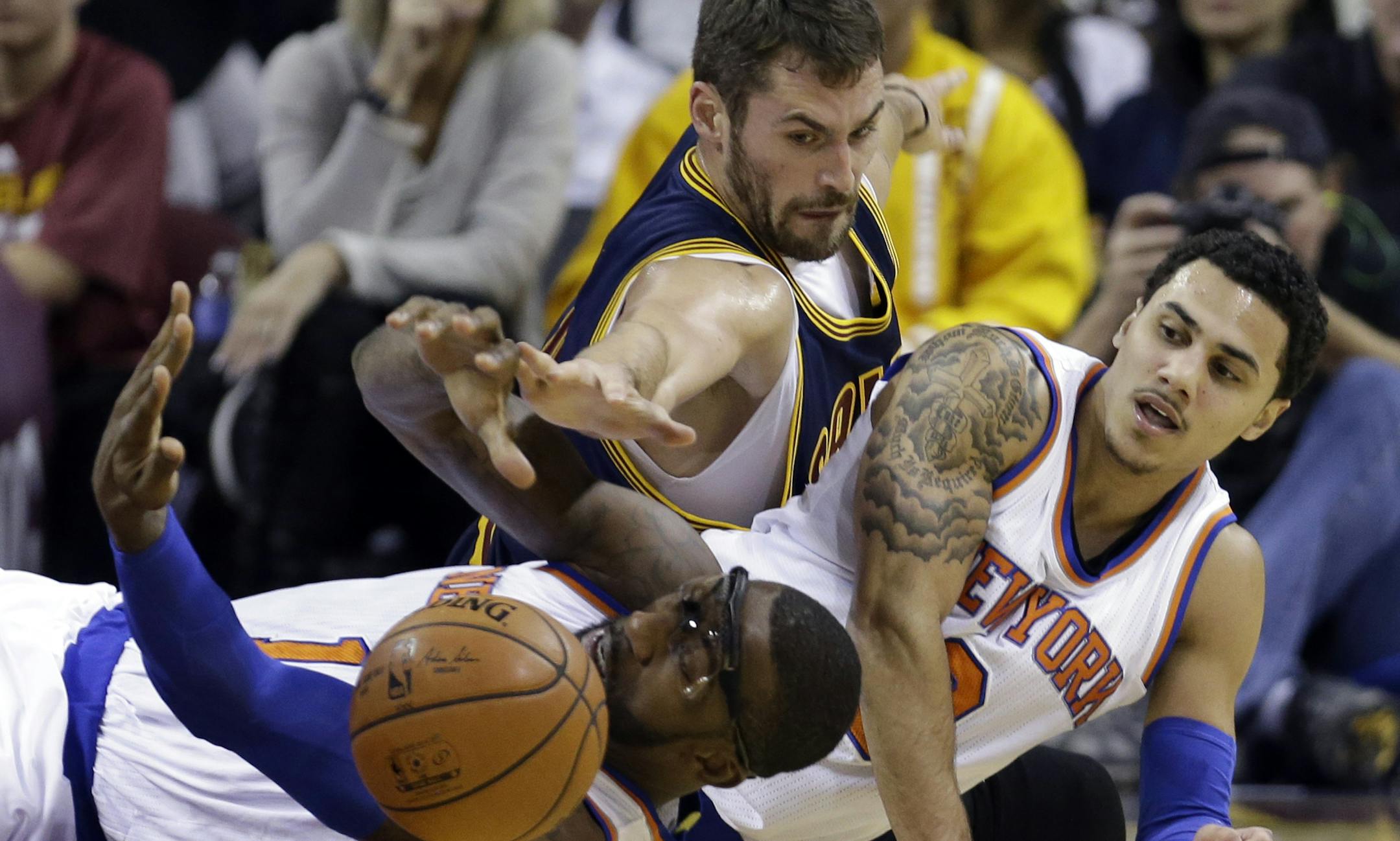 Cleveland Cavaliers' Kevin Love, top, battles for a loose ball with New York Knicks' Amar'e Stoudemire, left, and Shane Larkin in the first quarter of an NBA basketball game Thursday, Oct. 30, 2014, in Cleveland. (AP Photo/Tony Dejak)