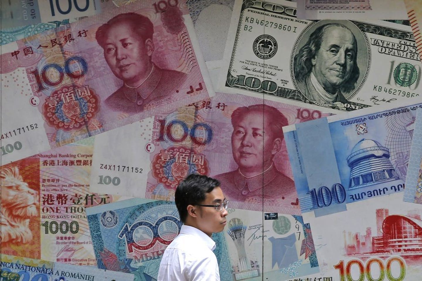 FILE - In this June 10, 2019, file photo, a man walks past a money exchange shop decorated with different banknotes at Central, a business district of Hong Kong. China's yuan fell Friday, Aug. 2, 2019, to its lowest level of the year against the dollar following U.S. President Donald Trump's threat of new tariffs on Chinese goods, coming close to breaking the politically sensitive level of seven to the U.S. currency.