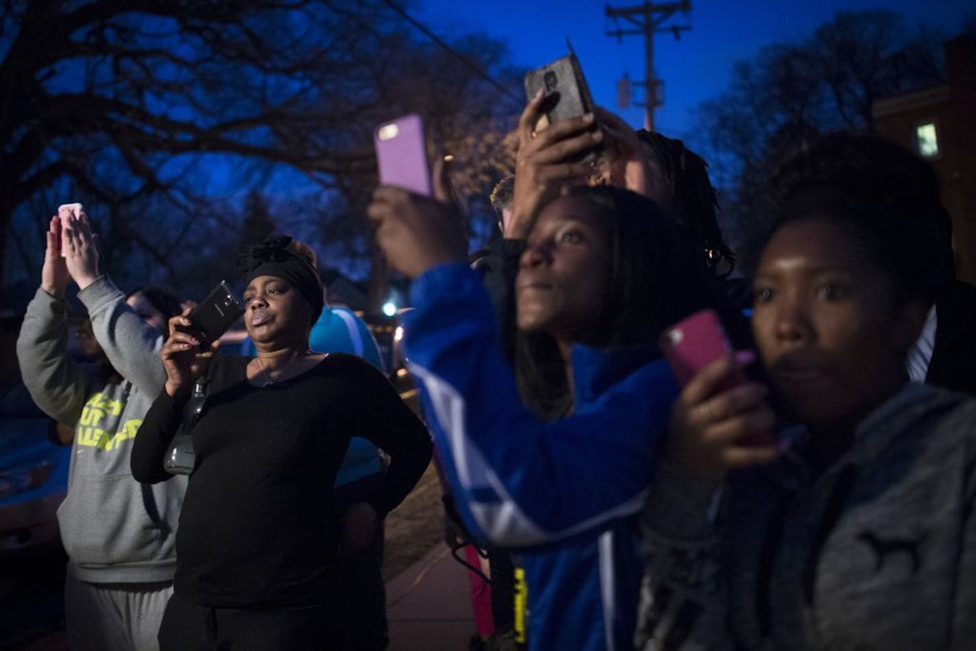 Onlookers watch a press conference held over an officer involved shooting at 38th Avenue North and Hubbard Avenue North in Robinsdale on Thursday, April 16, 2015.