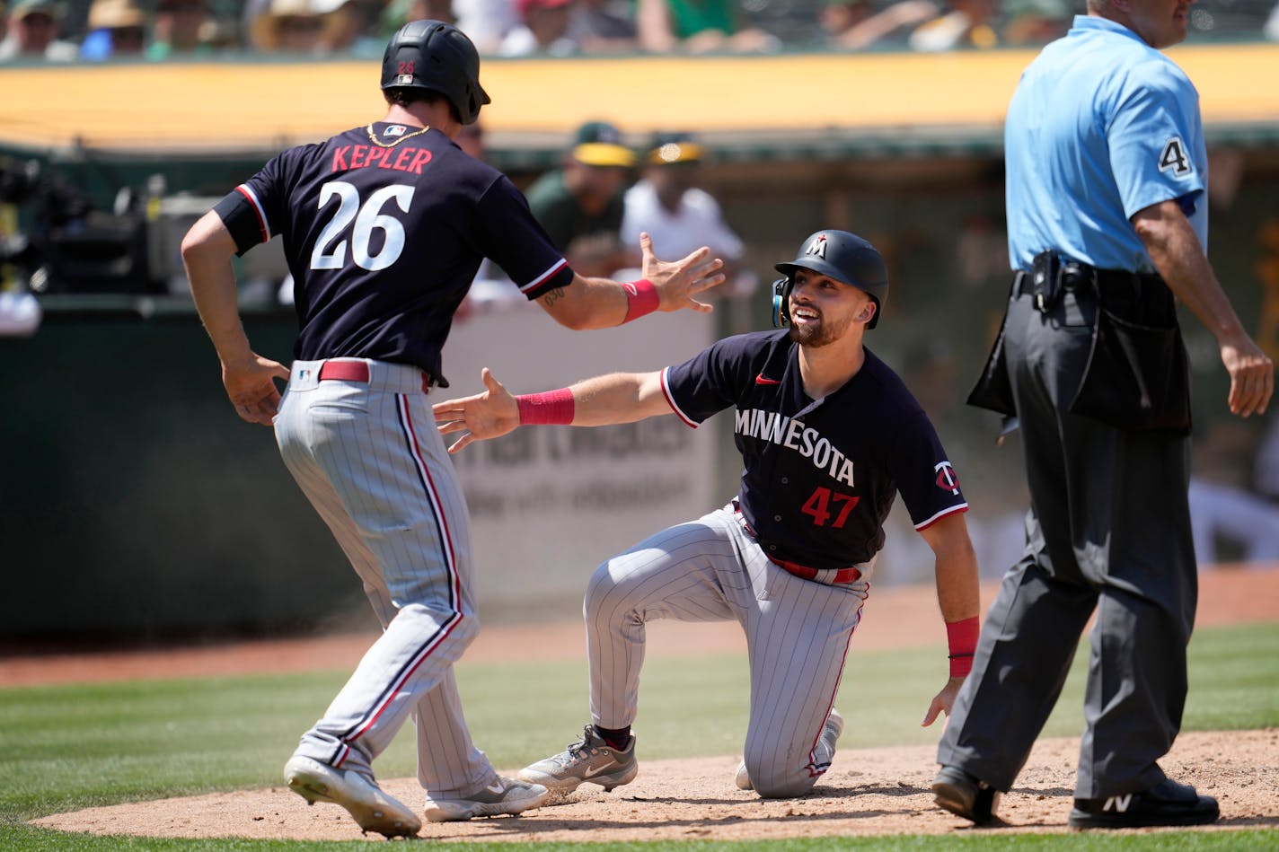 Minnesota Twins' Edouard Julien (47) is congratulated by Max Kepler (26) after they scored on a three run-double hit by Alex Kirilloff during the seventh inning of a baseball game against the Oakland Athletics in Oakland, Calif., Sunday, July 16, 2023. (AP Photo/Jeff Chiu)