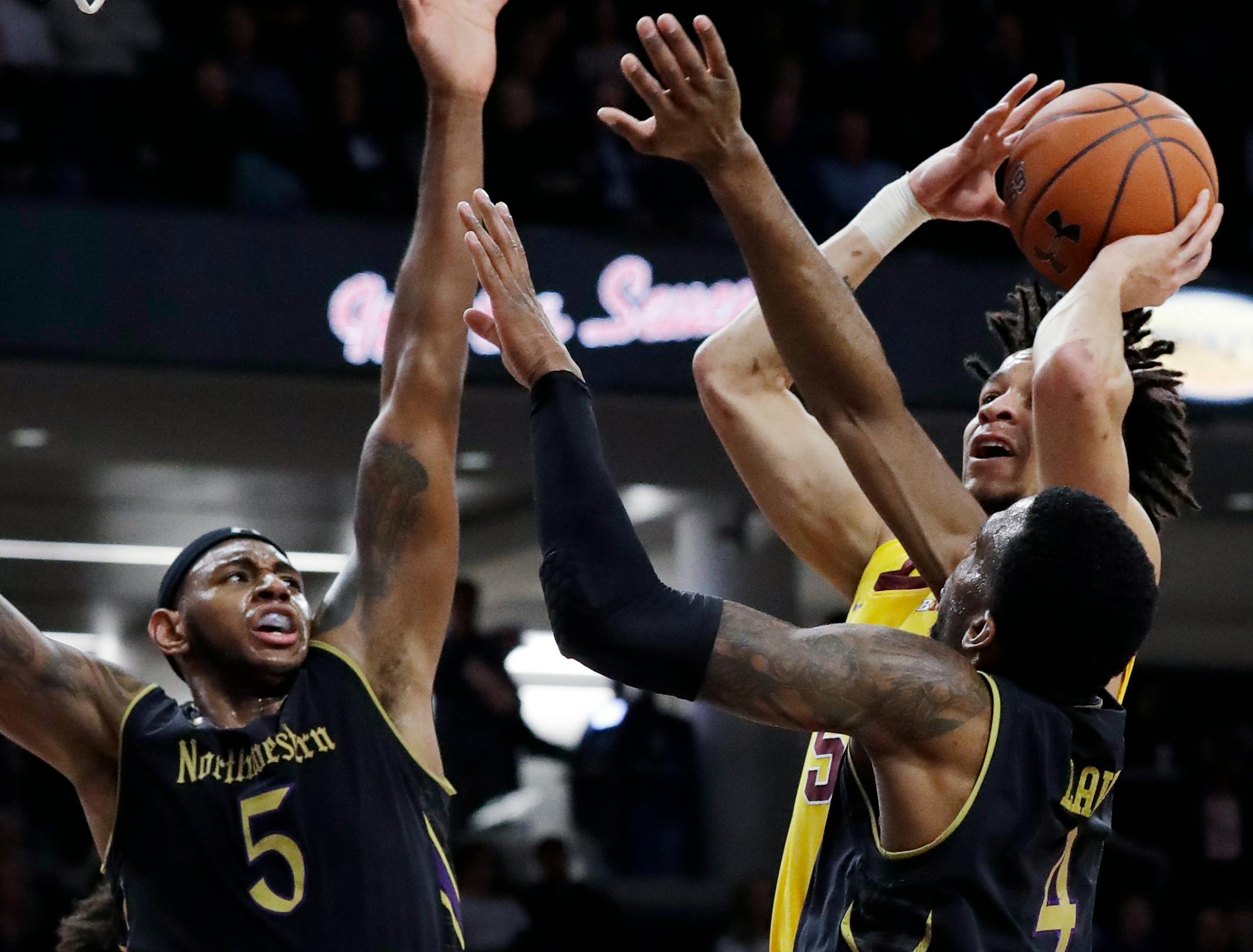 Gophers guard Amir Coffey shoots against Northwestern center Dererk Pardon, left, and forward Vic Law