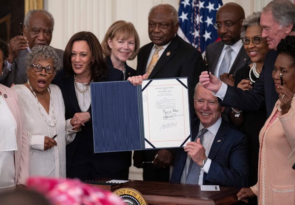 US Vice President Kamala Harris and Opal Lee, left, the activist known as the grandmother of Juneteenth, watch as US President Joe Biden holds the sig
