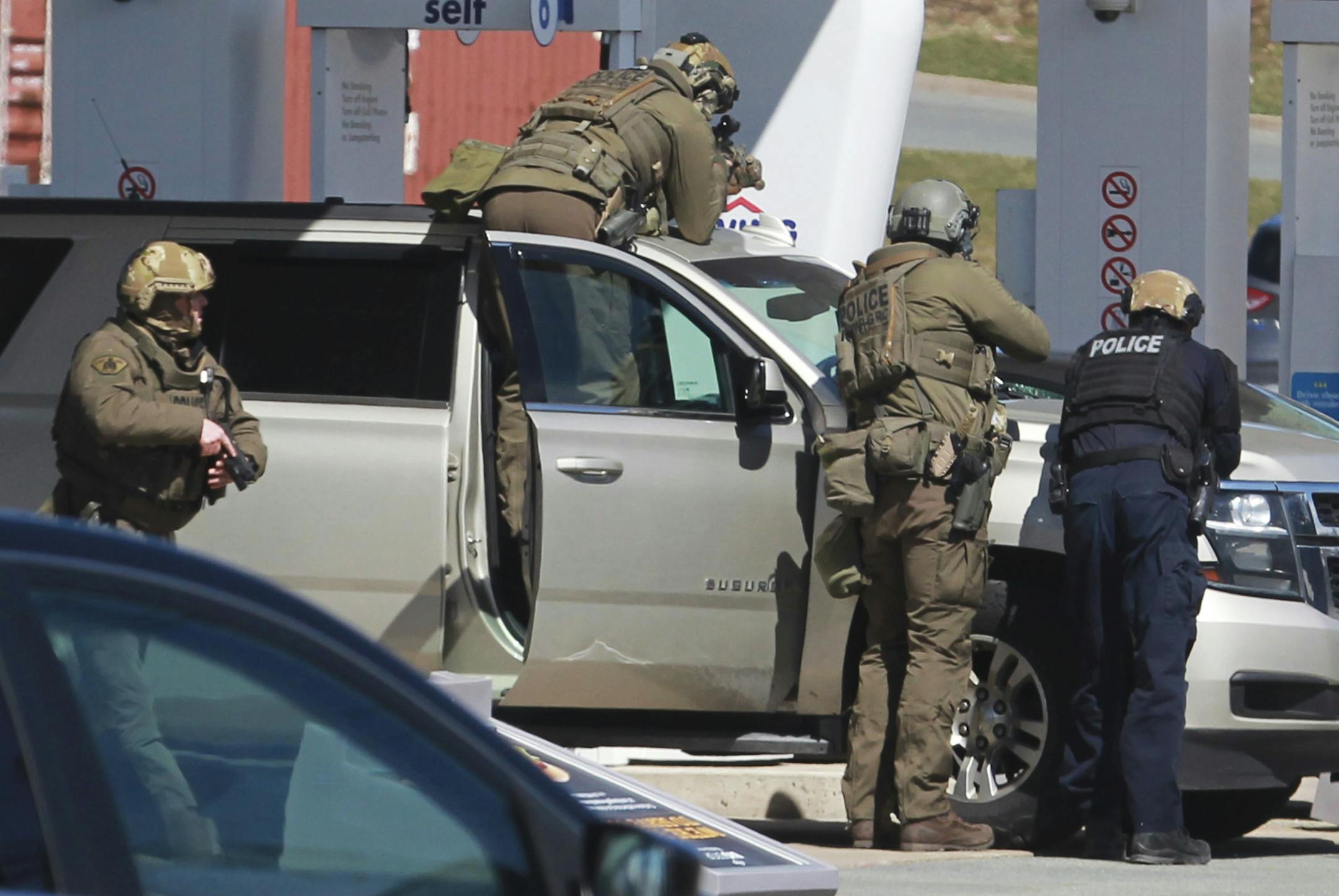 Royal Canadian Mounted Police officers surround a suspect at a gas station in Enfield, Nova Scotia, Sunday April 19, 2020. Canadian police say multiple people are dead plus the suspect after a shooting rampage across the province of Nova Scotia. It was the deadliest shooting in Canada in 30 years. (Tim Krochak/The Canadian Press via AP)
