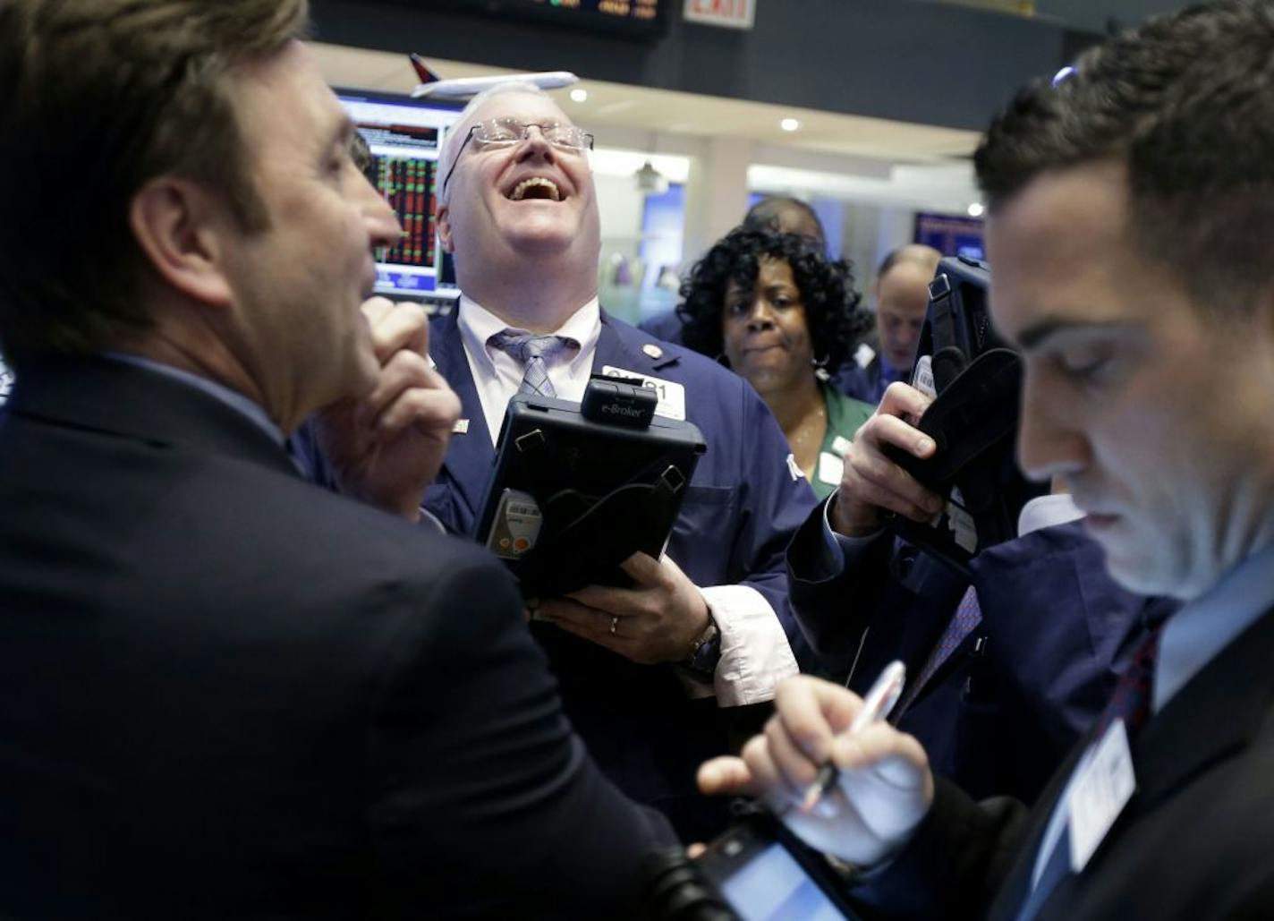 A trader laughs while working on the floor of the New York Stock Exchange in New York, Thursday, Jan. 31, 2013, when the Dow flirted with 14,000. On Friday, after a largely upbeat jobs report, the Dow climbed above 14,000 for a while.