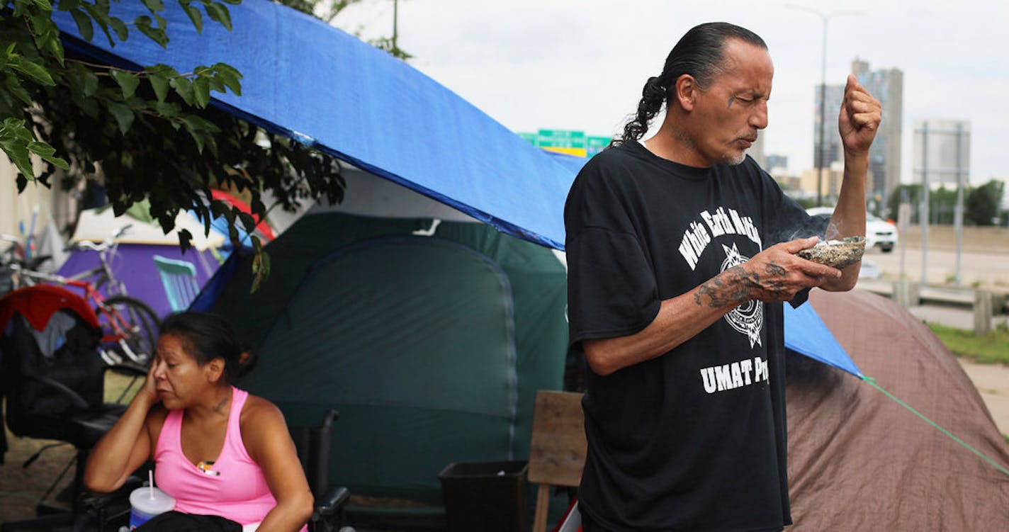 Yvonne, 32, sits in the makeshift camp just off of Hiawatha and Cedar Avenues as James Cross, founder of Natives Against Heroin, burns sage and prays in Minneapolis. The growing homeless encampment near the Little Earth housing project in Minneapolis has caused concern local health officials and American Indian leaders.