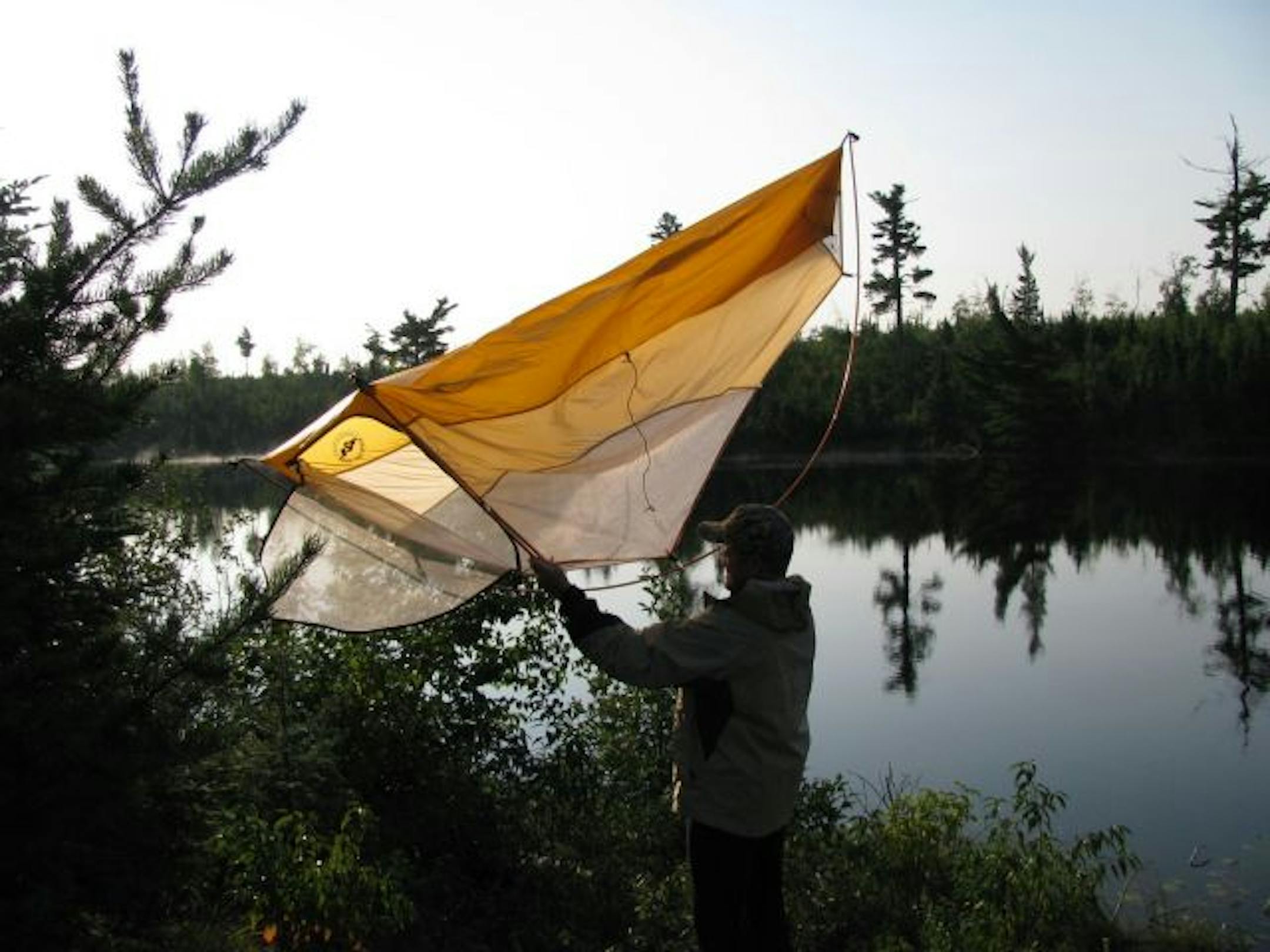 Larry Oakes shakes dew off his tent.