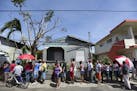 FILE - In this Sunday, Sept. 24, 2017 file photo, people affected by the passage of Hurricane Maria wait in line at Barrio Obrero to receive supplies 