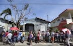 FILE - In this Sunday, Sept. 24, 2017 file photo, people affected by the passage of Hurricane Maria wait in line at Barrio Obrero to receive supplies 