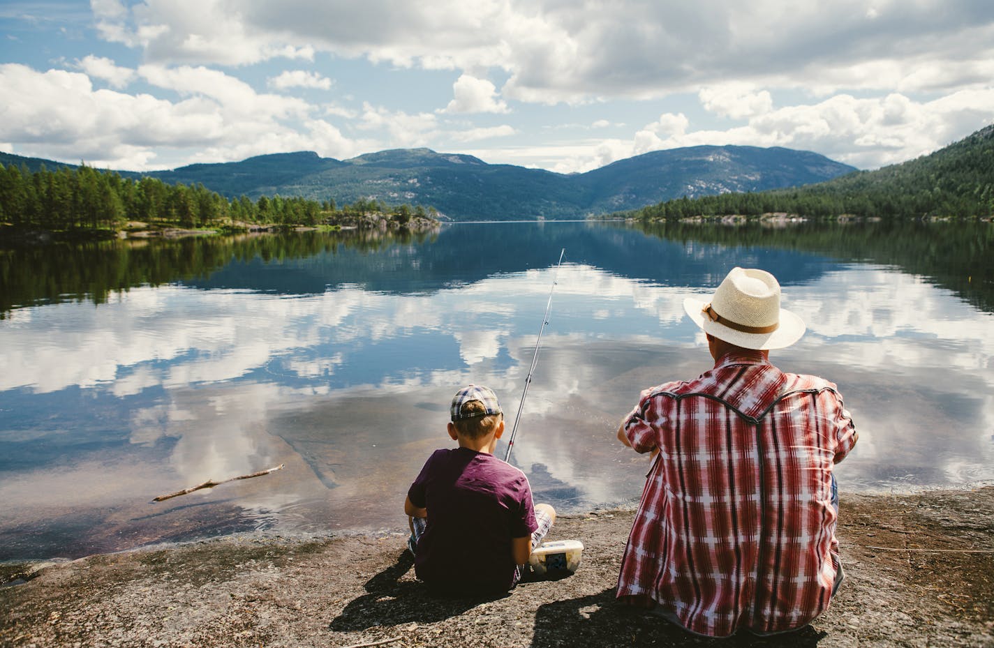 Grandfather is teaching his young grandson how to catch fish. Norway, July 2013.