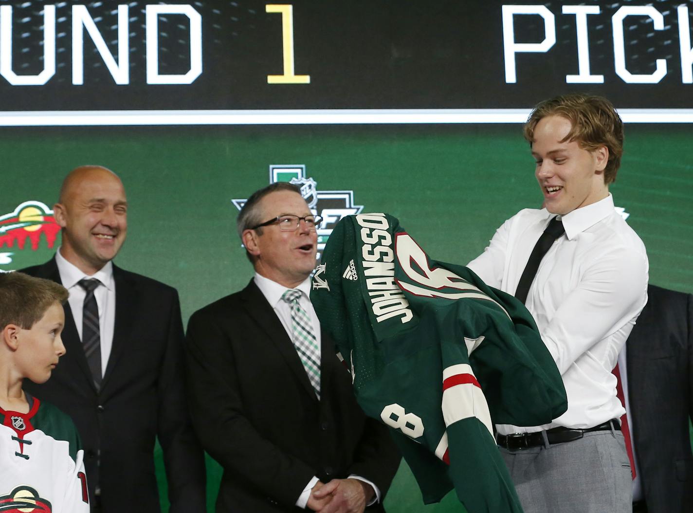 Filip Johansson, of Sweden, puts on a jersey after being selected by the Minnesota Wild during the NHL hockey draft in Dallas, Friday, June 22, 2018. (AP Photo/Michael Ainsworth)