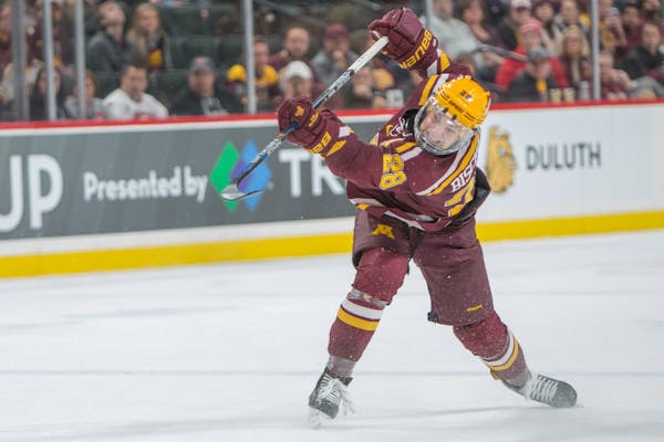 Minnesota Gophers defenseman Jake Bischoff (28) shoots the puck, teammate Brent Gates Jr. (10) would burry the rebound with 39 seconds left in the gam