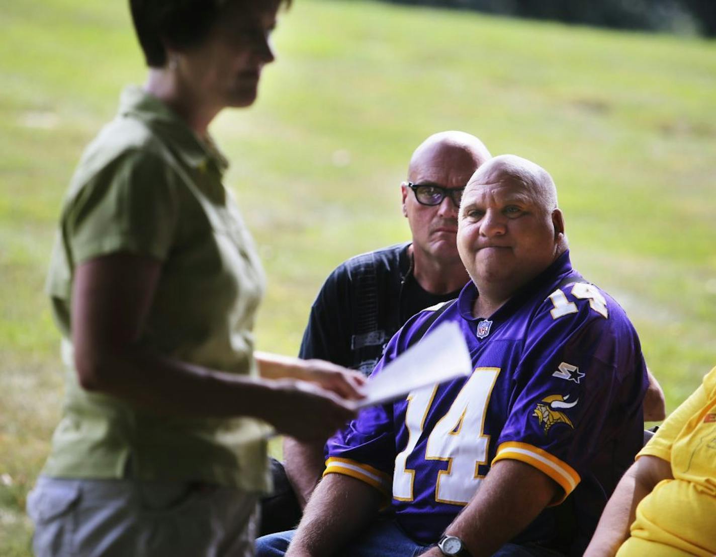 Nathan Miller, middle, and Lance Koenig, right, look on as State Rep. Mary Sawatzky, who is also a Special education teacher, read an official state apology to those gathered at the apology ceremony Saturday, Sept. 7, 2013, at Oak Knoll Cemetery in Willmar, MN. In it, the state apologized for, among other things, mistreatment and abuse of residents in state hospitals across the state -- which included burying the deceased with only numbers marking the grave and the forced sterilization of some o