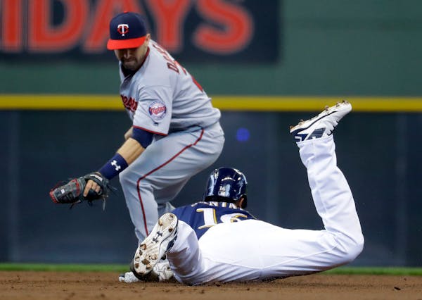 The Brewers' Domingo Santana slid safely into second for a double under the tag of Twins second baseman Brian Dozier during the first inning Thursday.