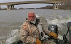 With the Interstate 494 bridge in the background, Dick "Griz'' Grzywinski guides his john boat downriver on the Mississippi. Sunny for a while, the fi