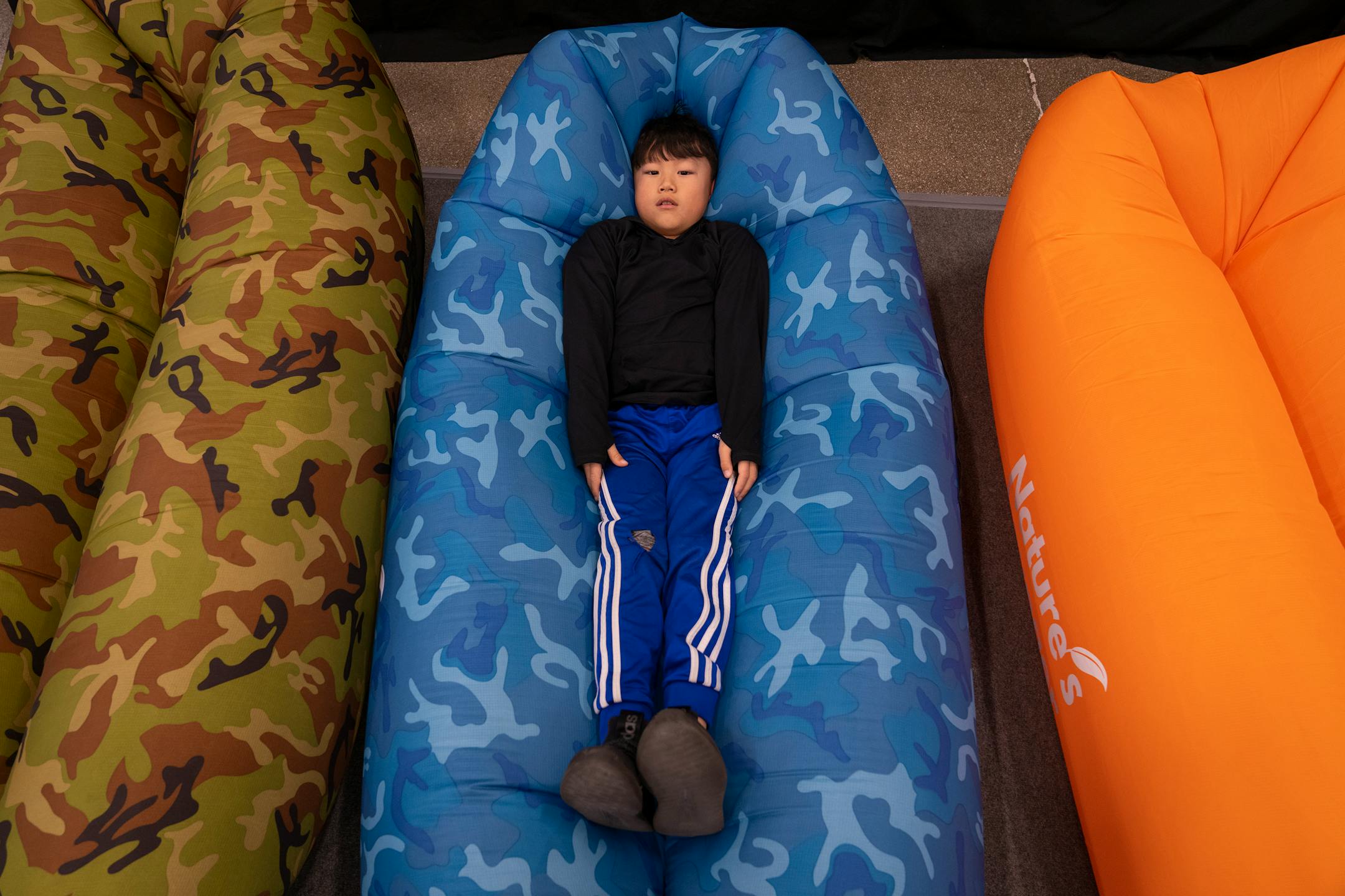Kenneth Thor, 8, of Brooklyn Park gets cozy inside a Nature's Lounger at the St. Paul Ice Fishing and Winter Sports Show in St. Paul, Minn. Friday, Dec. 1, 2023. ] LEILA NAVIDI • leila.navidi@startribune.com