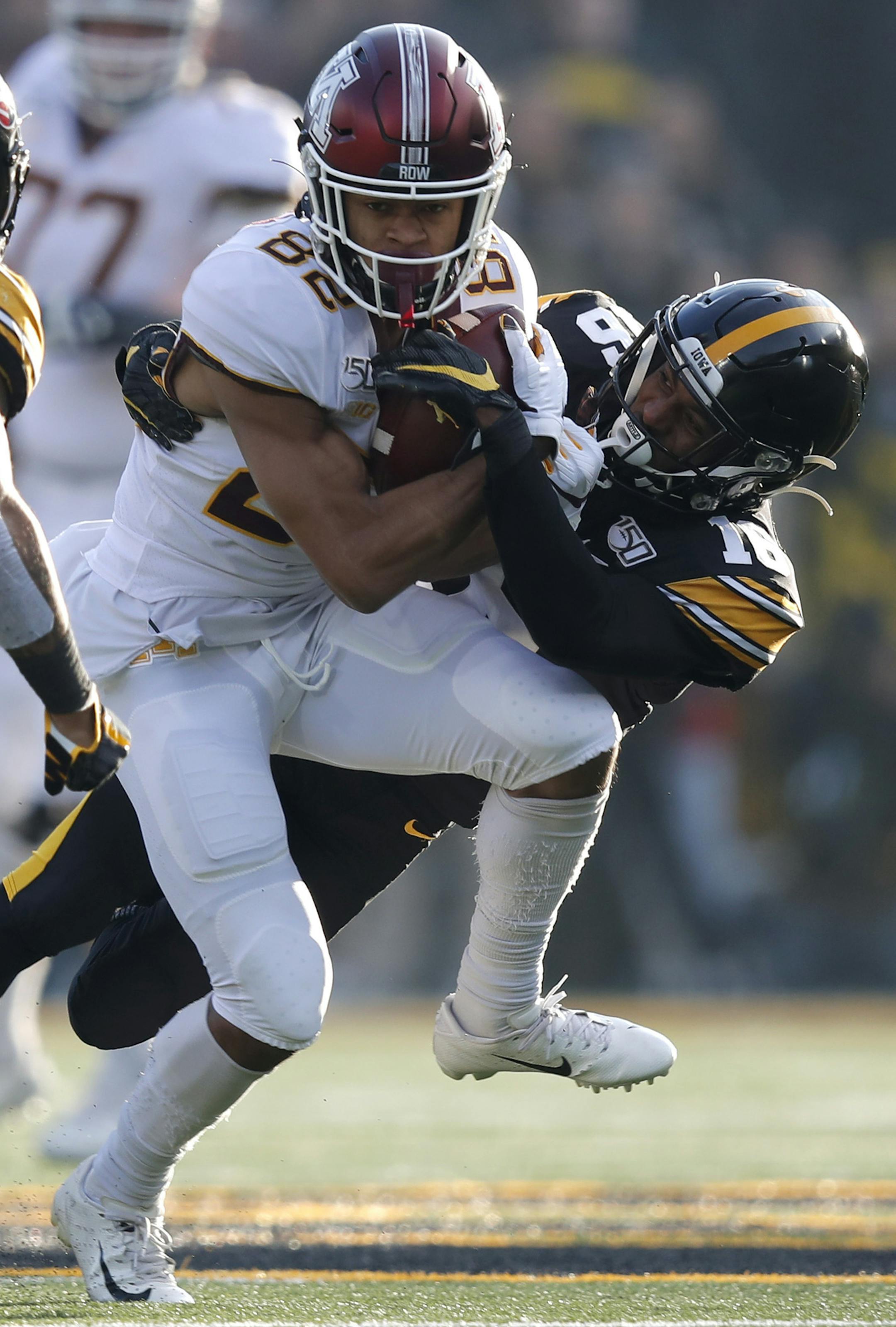 Minnesota wide receiver Demetrius Douglas, center, runs the ball as he is chased down by Iowa defensive back Terry Roberts as Iowa defensive back Geno Stone, left, comes in to assist during the first half of an NCAA college football game, Saturday, Nov. 16, 2019, in Iowa City, Iowa. (AP Photo/Matthew Putney)