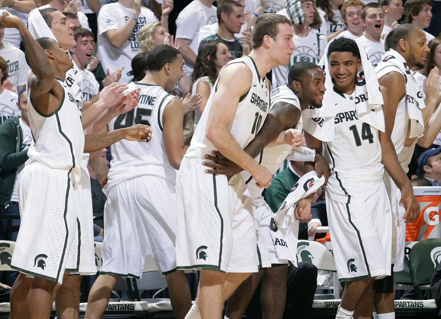 Michigan State's Keith Appling, left, Gavin Schilling, left rear, Denzel Valentine (45), Matt Costello (10), Branden Dawson, Gary Harris (14) and Adreian Payne celebrate on the bench during the first half of an NCAA college basketball exhibition game against Grand Valley State, Tuesday, Oct. 29, 2013, in East Lansing, Mich. Seated at right is coach Tom Izzo. Michigan State won 101-52. (AP Photo/Al Goldis)