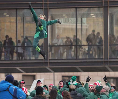 A member of the St. Paul Bouncing Team goes skyward during  St. Paul's St. Patrick's Day parade Friday, March 17, 2023 in downtown St. Paul, Minn.