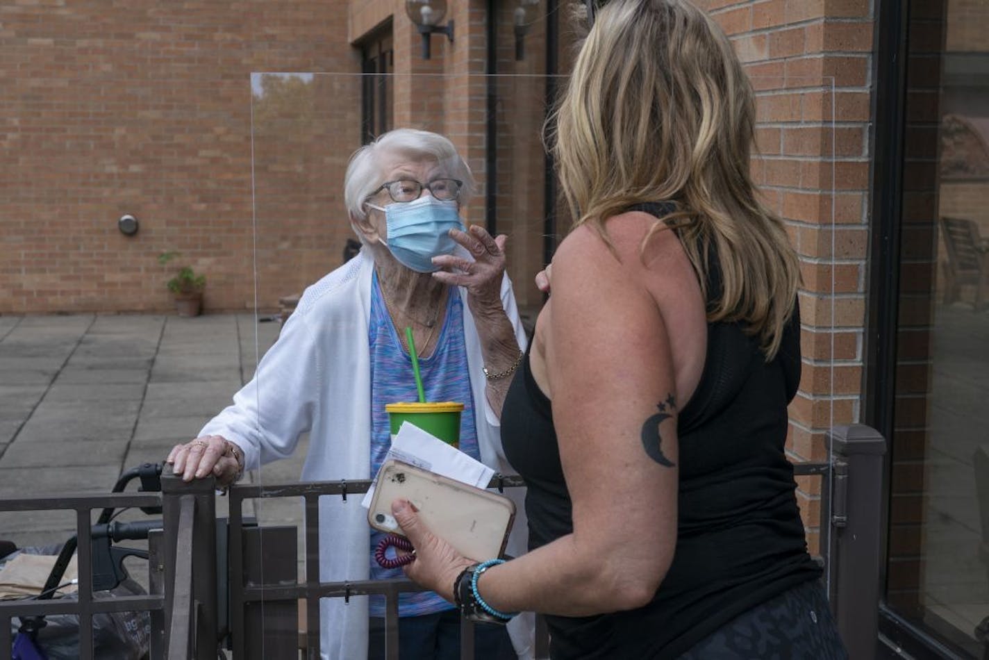 Kay Foley, 88, left, and her daughter Chris Coverdale blew kisses to each other after an outdoor visit in July at Jones-Harrison nursing home. Some facilities have moved to curb outdoor visits, which began in June, because of a recent surge of coronavirus cases.