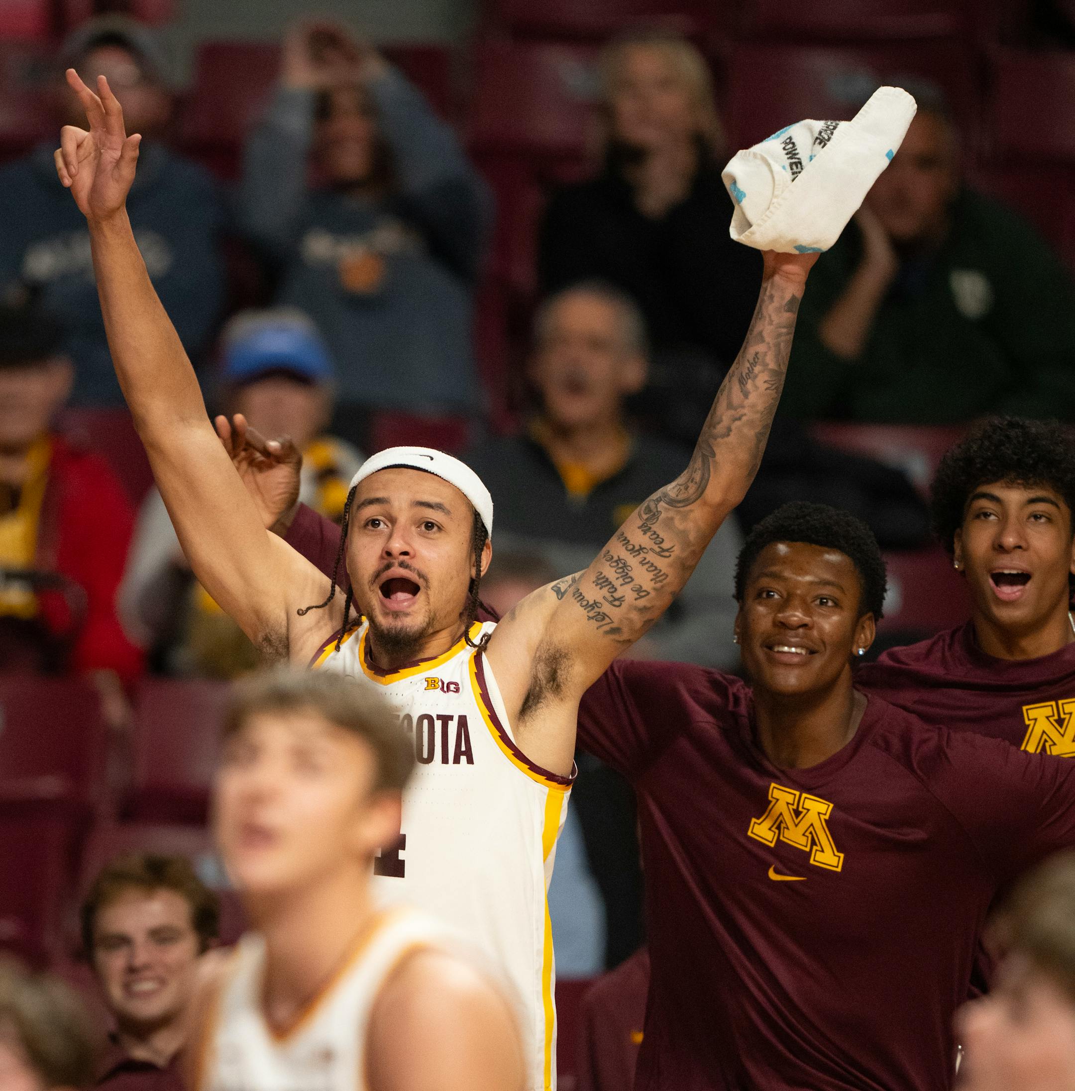 Minnesota Gophers forward Pharrel Payne, center, and guard Cam Christie, right, joined guard Braeden Carrington (4) in cheering their teammates from the bench in the second half.