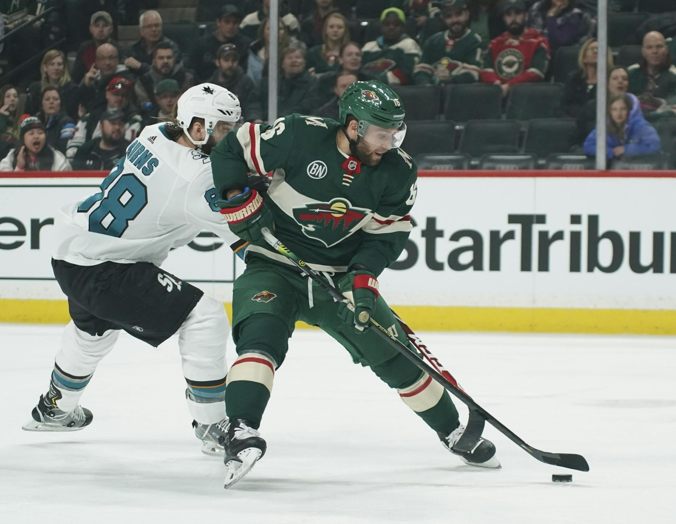 With San Jose Sharks defenseman Brent Burns (88) checking him from behind, Minnesota Wild left wing Jason Zucker (16) lined up a first period shot.