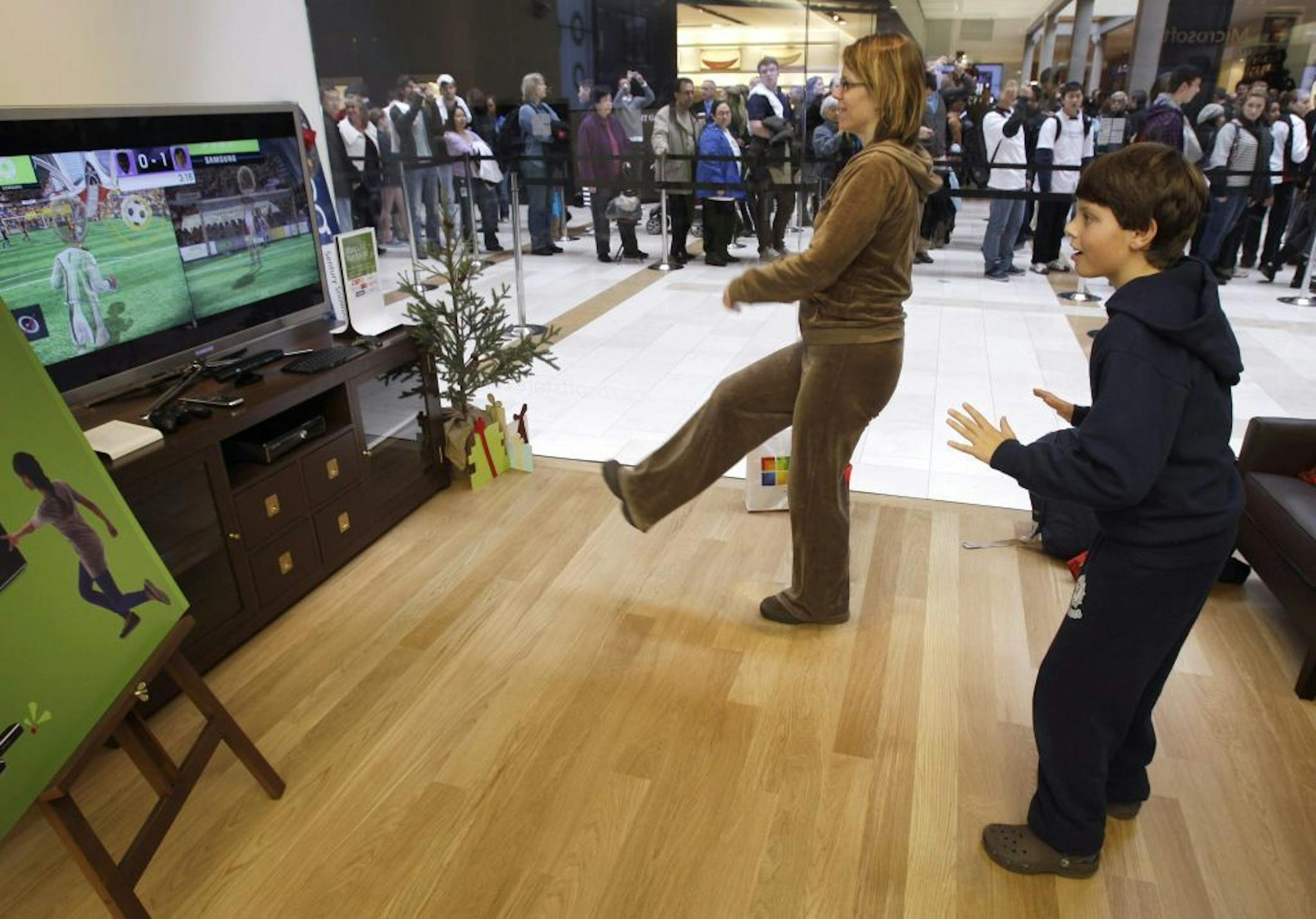 Aidan Bullard, 9, right, plays soccer on an Xbox 360 Kinect with his mother, Molly Bullard, second from right, at the grand opening of a Microsoft Store, Thursday, Nov. 18, 2010, in Bellevue, Wash. The store is the seventh Microsoft Store to open in the U.S., but the event garnered extra attention due to Microsoft's nearby headquarters in Redmond, Wash.