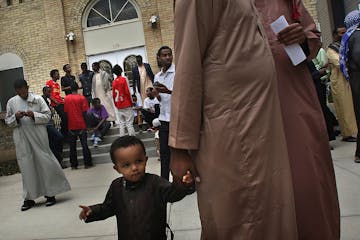 Abdullahi Hassan, 18 months, waited patiently while holding the hand of his father, Bashir Farah, after a Friday afternoon prayer service at the Islam