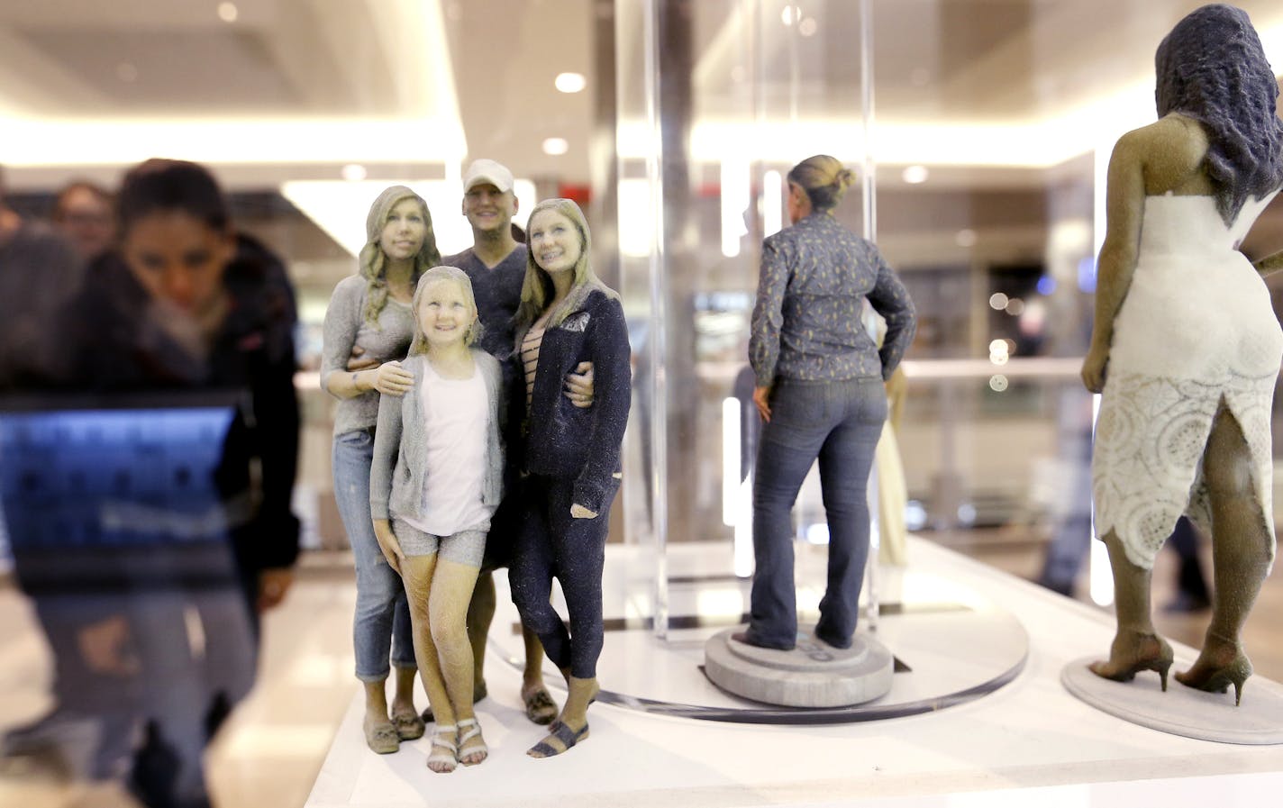 Shoppers at the Mall of America stopped to take a look at the figurines at ME 3D a new store that makes 3D statues of people and pets. ] CARLOS GONZALEZ &#xef; cgonzalez@startribune.com - November 25, 2015, Bloomington, MN, Mall of America, A new retail concept at the Mall of America uses 90 cameras ad a 3D printer to make little statues of people (and their pets), ranging in price from $95 to $645. The store, Me 3D, opened Oct. 21.