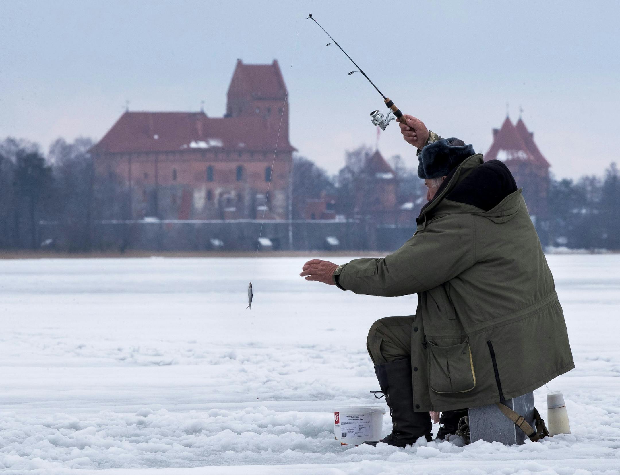 A local fisherman fishes on a frozen, snow-covered Galve lake as temperatures are just 2 degrees Celsius (35,6 degrees Fahrenheit) in Trakai, some 30km (14 miles) west of the capital Vilnius, Lithuania, Saturday, March 10, 2018. Trakai Island Castle in the background.(AP Photo/Mindaugas Kulbis) ORG XMIT: XMK101