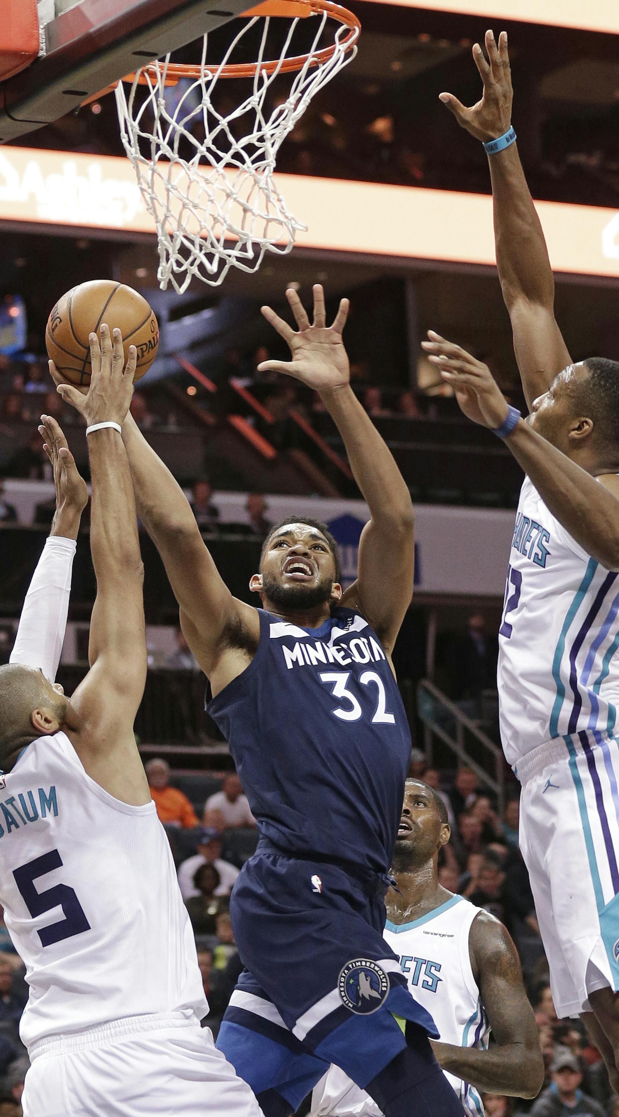 Minnesota Timberwolves' Karl-Anthony Towns (32) shoots between Charlotte Hornets' Nicolas Batum (5) and Dwight Howard (12) during the second half of an NBA basketball game in Charlotte, N.C., Monday, Nov. 20, 2017. (AP Photo/Chuck Burton)