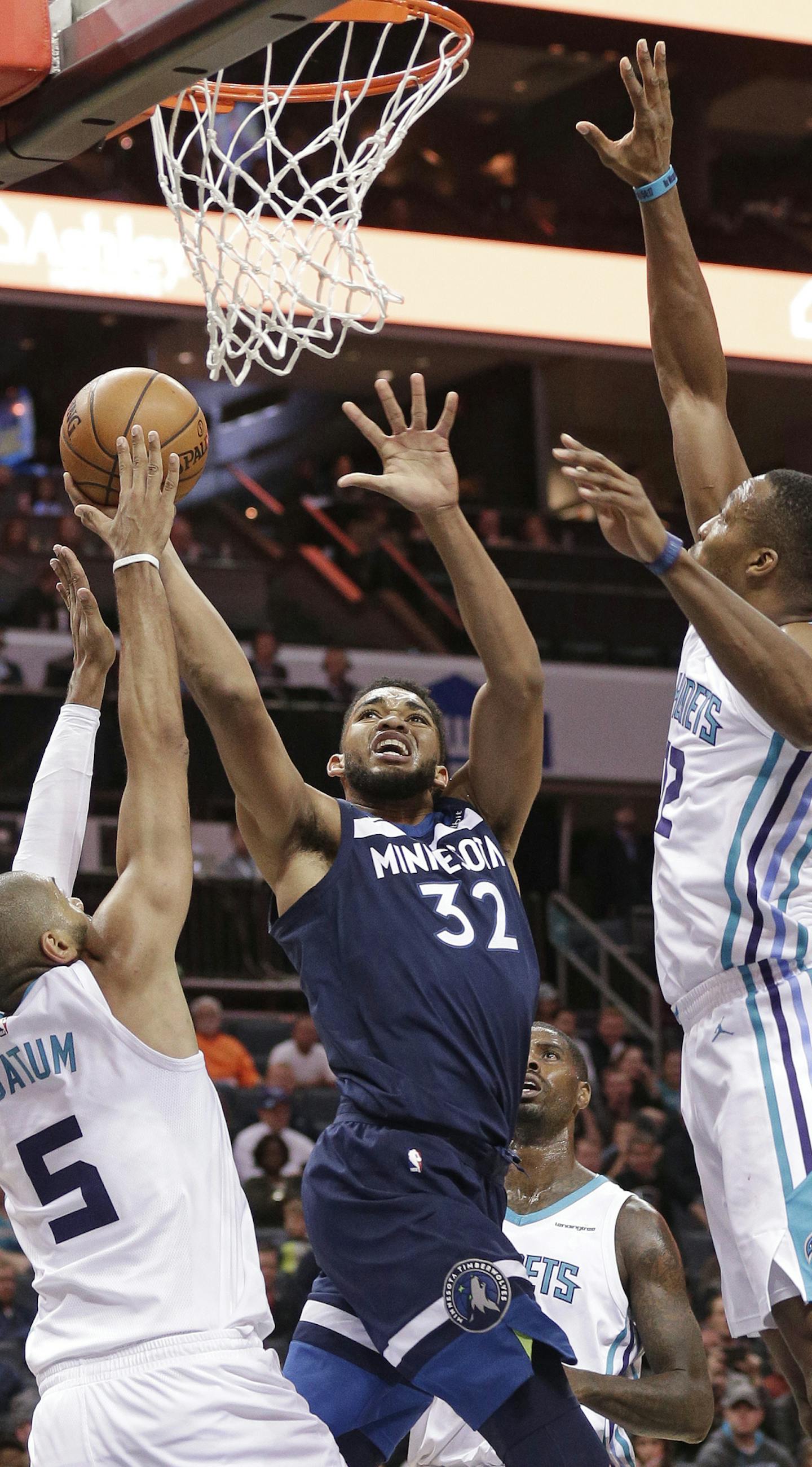 Minnesota Timberwolves' Karl-Anthony Towns (32) shoots between Charlotte Hornets' Nicolas Batum (5) and Dwight Howard (12) during the second half of an NBA basketball game in Charlotte, N.C., Monday, Nov. 20, 2017. (AP Photo/Chuck Burton)