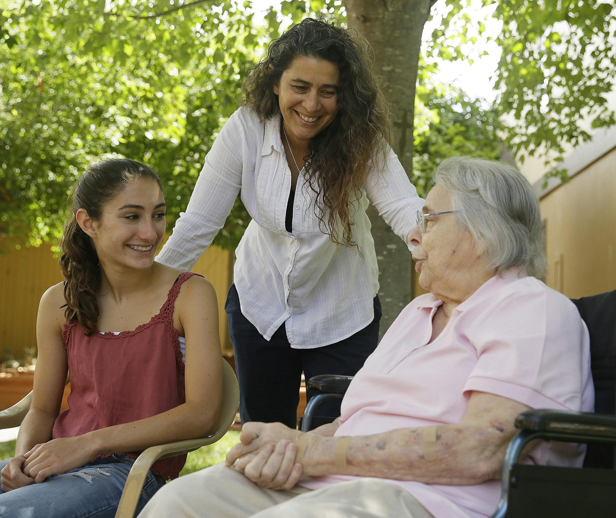 In this photo taken Monday, July 6, 2015, Kamila Al-Najjar, center, visits with her mother, Joan Groen, right, at her assisted living facility as her daughter, Inanna Al-Najjar, 14, left, looks on in Santa Rosa, Calif. Caught between kids and aging parents, a new poll shows the sandwich generation worries more than most Americans their age about how they'll afford their own care as they grow older. (AP Photo/Eric Risberg)