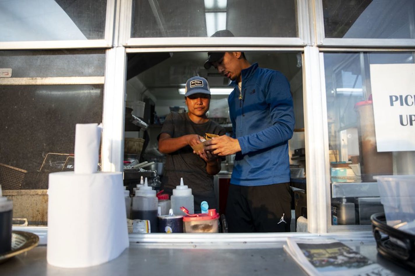 Joy Phonesavanh from Warroad, MN hands food for a customer to her cousin and employee, Lucky Kounlavong inside her food truck, Sap Sap. Joy hopes to purchase a building in Warroad to make a brick and mortar restaurant.