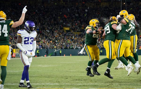 Minnesota Vikings free safety Xavier Woods ,(23) walks off the field as Packers offensive line celebrates Green Bay Packers running back A.J. Dillon (