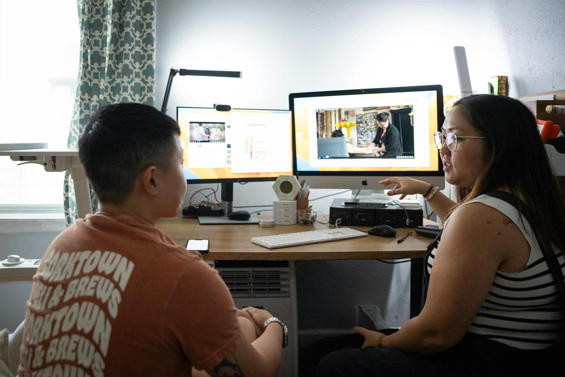 Joua, right, and video editor Cameron PajYeeb Yang review video for the documentary they're working on.