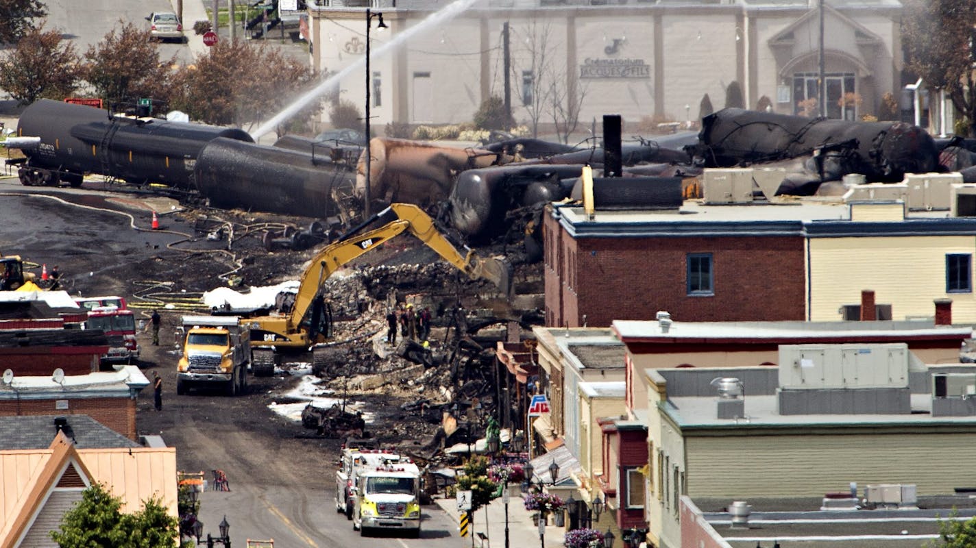 Searchers dig through the rubble for victims of the inferno in Lac-Megantic, Quebec, Monday, July 8, 2013, as firefighter continue to hose down tanker cars to prevent explosions. A runaway train derailed igniting tanker cars carrying crude oil early Saturday. (AP Photo/ THE CANADIAN PRESS,Ryan Remiorz)