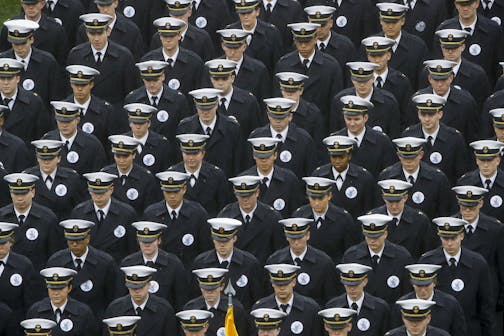 FILE - In this Dec. 14, 2019 file photo, Navy midshipmen march onto field ahead of an NCAA college football game between the Army and the Navy in Philadelphia. A military investigation finds that hand gestures used by cadets and midshipmen during the Army-Navy game broadcast had nothing to do with white supremacy. The investigation, which included interviews and background checks, determined that two freshmen were taking part in a &#x201c;sophomoric&#x201d; game that had &#x201c;no racist intent