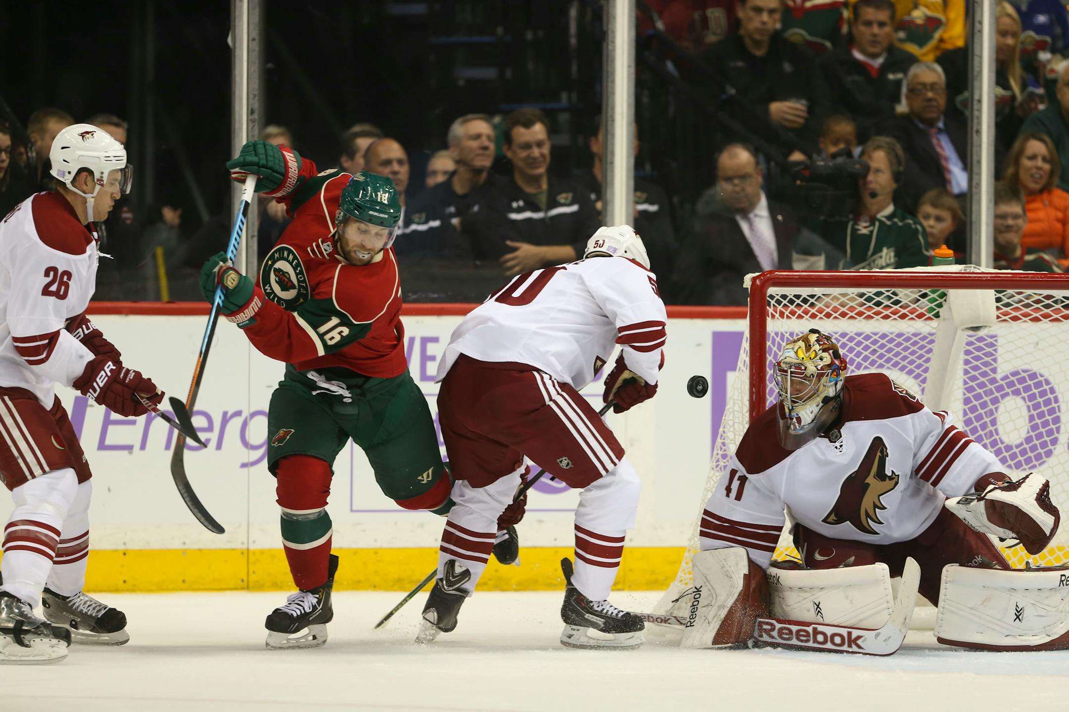 Minnesota Wild left wing Jason Zucker (16) tried to get a stick on the flying puck while defended by the Coyotes' Antoine Vermette (50) in front of Arizona goalie Mike Smith (41).