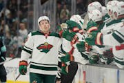 Minnesota Wild center Rem Pitlick, center, greets teammates at the bench after he scored a goal against the Seattle Kraken in the first period of an N