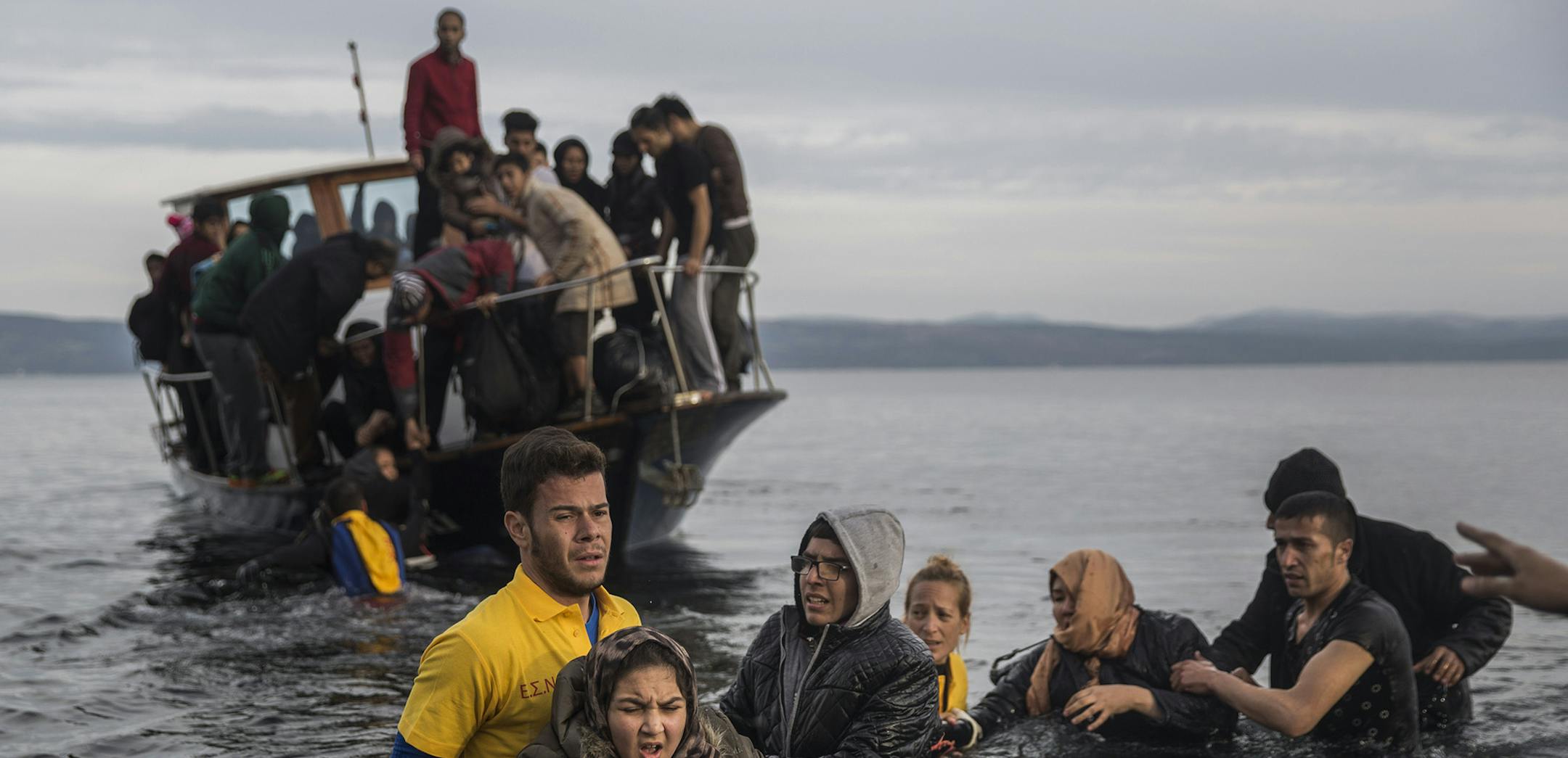 Greek lifeguards help refugees and migrants to disembark from a small boat after their arrival from the Turkish coast on the northeastern Greek island of Lesbos Monday, Nov. 16, 2015. Greek authorities say 1,244 refugees and economic migrants have been rescued from frail craft in danger over the past three days in the Aegean Sea, as thousands continue to arrive on the Greek islands. (AP Photo/Santi Palacios) ORG XMIT: MIN2015111608284507
