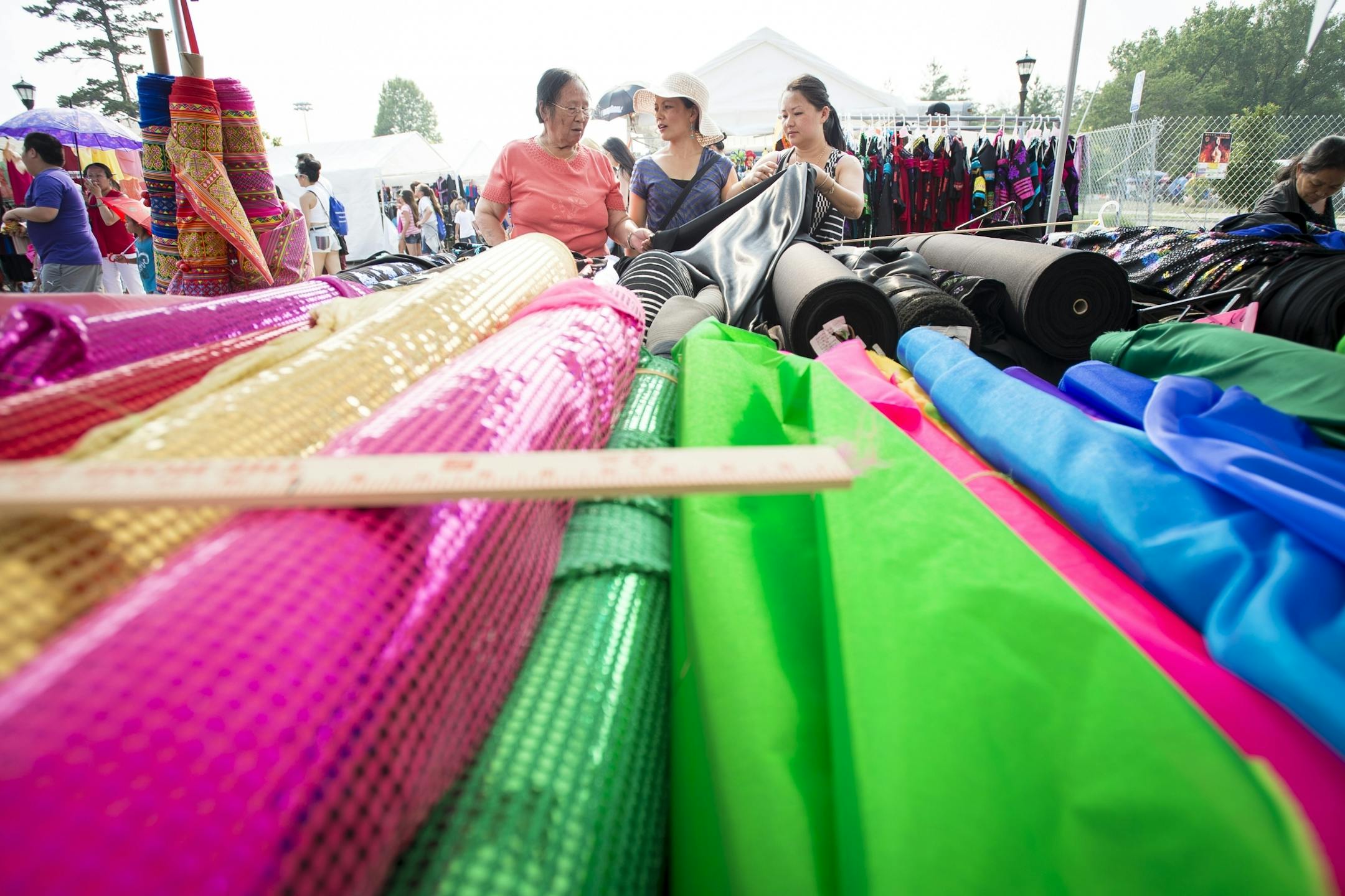 From left, Lee Ying, of St. Paul, and Joua Vue were helped by Pania Yang, with All Fabrics, with picking out fabrics used for the creation of traditional Hmong dresses worn by women during the Hmong New Years and weddings.
