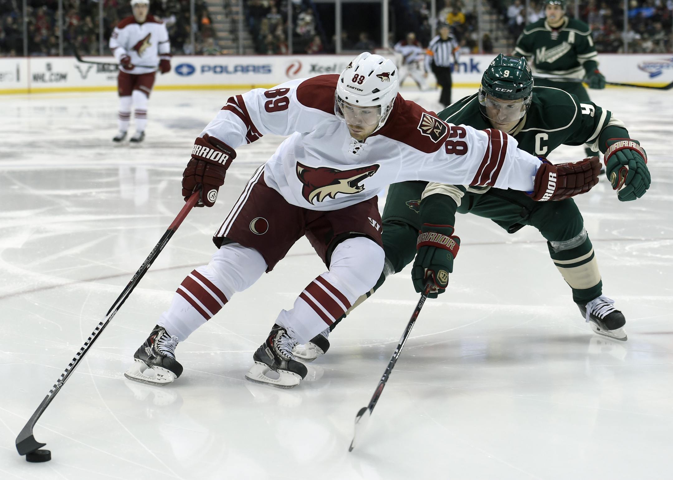Arizona Coyotes left wing Mikkel Boedker (89), of Denmark, keeps the puck away from Minnesota Wild center Mikko Koivu (9), of Finland, during the second period of an NHL hockey game Saturday, Jan. 17, 2015, in St. Paul, Minn. (AP Photo/Hannah Foslien)