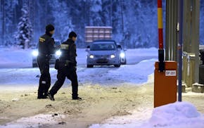 FILE - Finnish border guards walk through snow at Vaalimaa border check point between Finland and Russia at night in Virolahti, Finland, on Dec. 15, 2