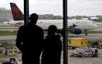 In this Tuesday, April 14, 2015 photo, travelers watch as a plane taxis at Hartsfield-Jackson Atlanta International Airport in Atlanta. After years of